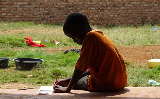 Boy writing outside in Uganda