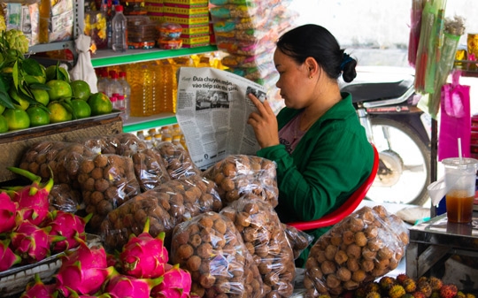 Woman reading newspaper next to food
