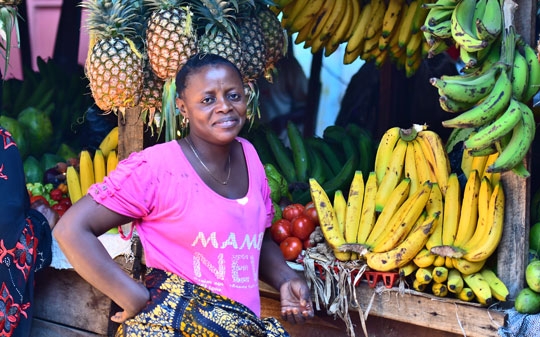 Woman wearing pink tshirt next to fruits in Tanzania